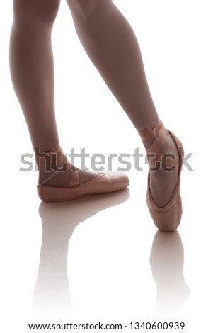 The legs of a ballerina in beige pointe doing poses on a white background