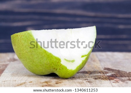 Bitten off a piece of pear on a wooden cutting board. Closeup of eating fruits