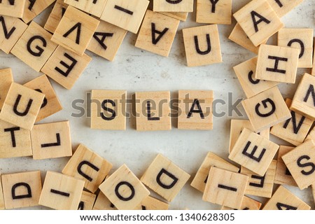 Top down view, pile of square wooden blocks with letters SLA (stands for Service Level Agreement) on white board. 
