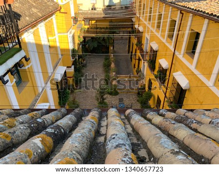 View from the tile roof with moss on the cozy Sevillian courtyard and the yellow walls of ancient buildings
