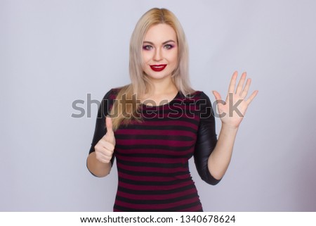 Portrait of smiling blonde woman wearing red and black dress standing over white background in studio