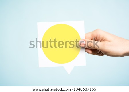 Woman holding a speech bubble with a yellow circle on blue background. Concept of yellow traffic light.