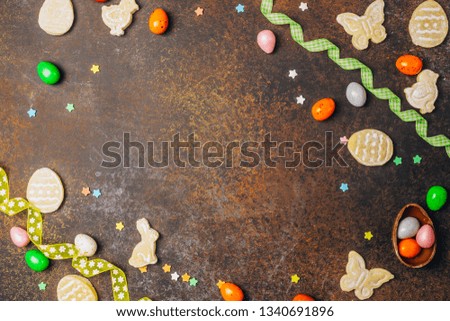 sugar easter cookies with colorful chocolate shape of eggs candy on dark background. Top view