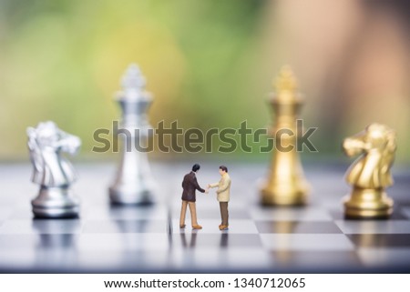 Business decision making concept. Miniature people : small businessman figure standing against chessboard wall with chess pieces