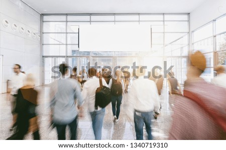 Crowd of anonymous people walking at a trade show, with copy space banner
