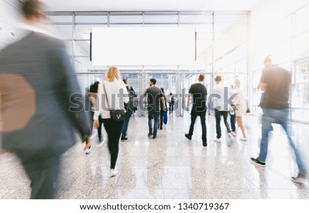 crowd of anonymous blurred people at a trade fair, including banner with Copy space