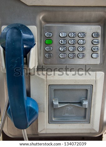 Old public telephone with blue receiver.
