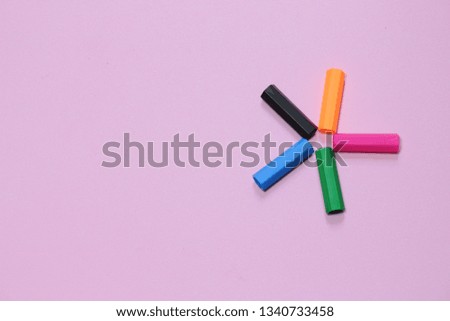 Five colorful pen cap on a pink millennial background with copy space to insert the text. Office stuff. Minimalism. Metaphor to teamwork and hierarchy