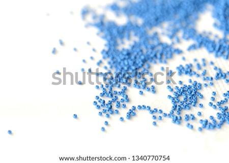 Seed beads dark blue color scattered on a textile background close up