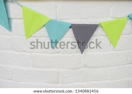 White brick wall with colorful pastel paper flag decoration. Closeup textured background with copy space for text. Fancy Childern  bedroom play space or living room.