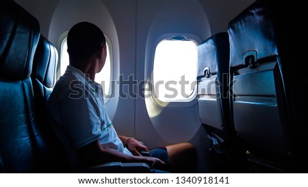 Young passenger looking out through window of the airplane. Royalty-Free Stock Photo #1340918141