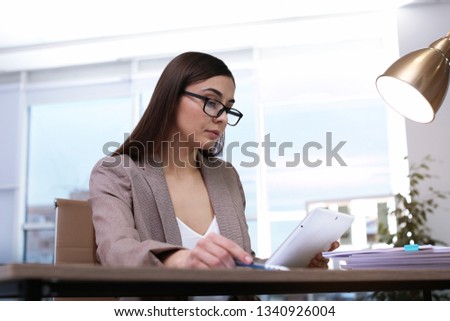 Businesswoman working with tablet and documents at table in office