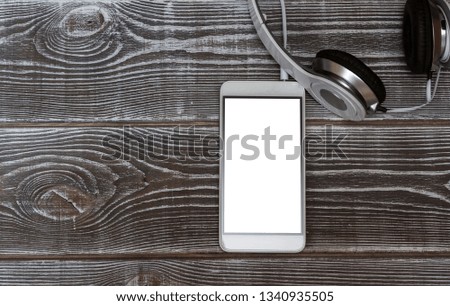 Headphones, smartphone on a wooden table background. Internet, listening to music, education.