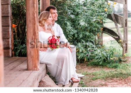 Bride and groom are sitting on the threshold of a wooden house