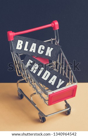 A trolley on a black background with labels containing the inscription "Black Friday". Toned. Vertical