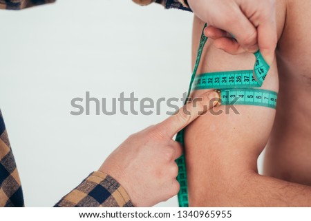 a man with a tape meter tape measure the circumference of biceps Royalty-Free Stock Photo #1340965955