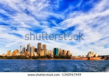 Cityscape of Sydney city CBD high-rise tower buildings on waterfront of SYdney harbour under deep blue sky on a sunny day.