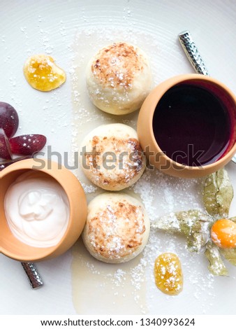 Ukrainian curd pancakes (syrniki, russian syrniki) on the plate with jam and sour cream. High resolution picture perfect for cooking book, receipt book or food magazine.