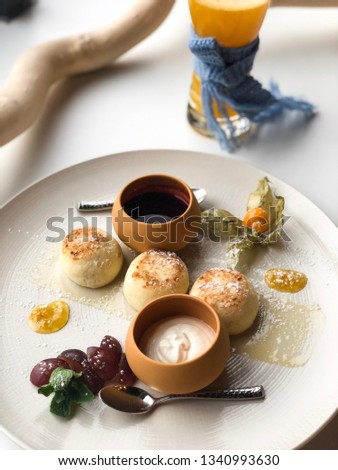 Ukrainian curd pancakes (syrniki, russian syrniki) on the plate with jam and sour cream. High resolution picture perfect for cooking book, receipt book or food magazine.