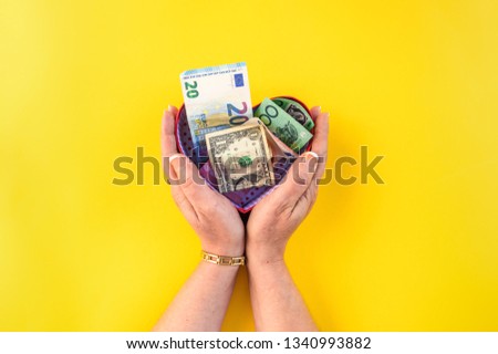 A woman hands holds paper money inside heart or love gift box