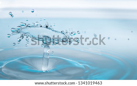 close up of a drop falling and impacting a body of water and forming beautiful droplets