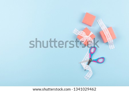 Pink gift boxes with lace and scissors on blue color background. Minimal Gift wrap, happy birthday  background.