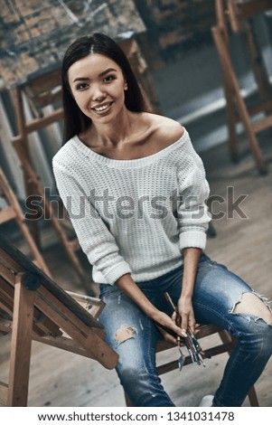 Young beautiful woman painting artist while working in a studio, smiling to the camera