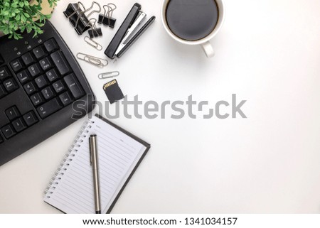 Top view of white office desk with black keyboard,a cup coffee,notepad,clip paper. Top view of copy space.