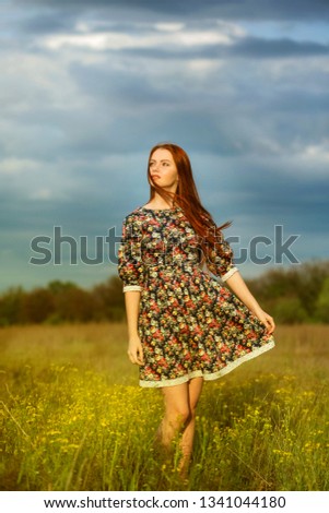 young redhead girl with a bouquet of flowers in the rays of the setting sun in the field of wild flowers