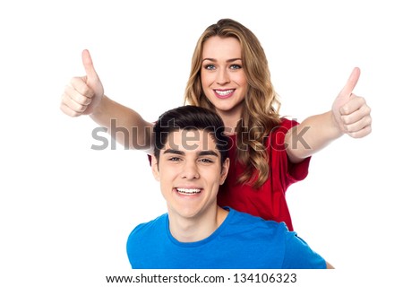 Pretty female showing double thumbs up  while enjoying piggyback ride.