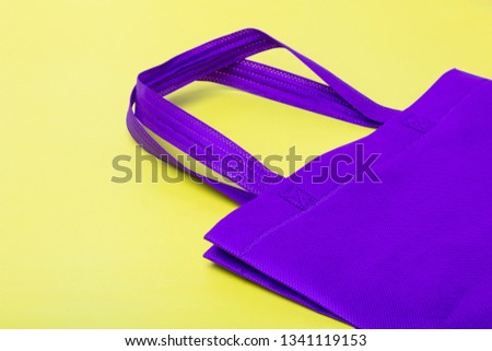 Purple plain flex eco cloth bag with sign of plastic free or no plastic campaign on yellow background with copy space.