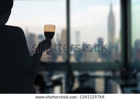 Female with glasse of red wine in the apartment with New York city view. 