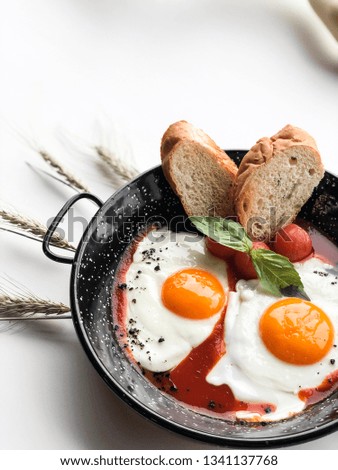 Fried eggs with baguette in an iron plate. High resolution picture perfect for cooking book, receipt book or food magazine.