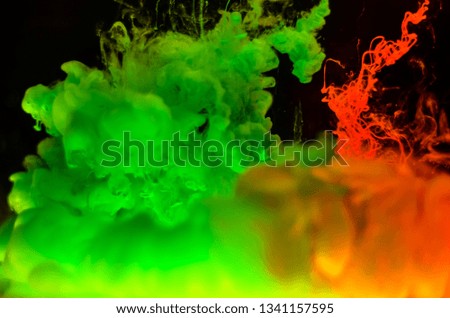 Color paint drops in water. Ink swirling underwater. Cloud of silky ink collision on black background.  