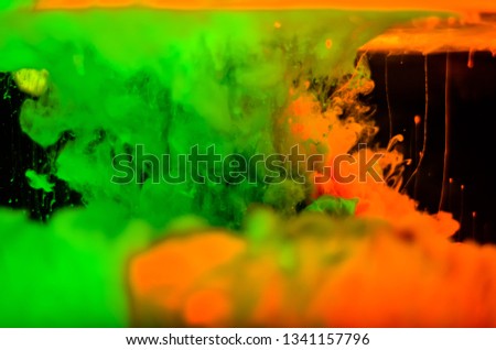Color paint drops in water. Ink swirling underwater. Cloud of silky ink collision on black background. 