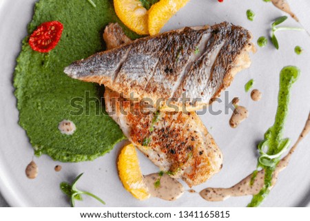 Closeup fried sea bass fillet with green pea puree, tomatoes, sauce, orange slices. Concept professional photography, photo session new menu, profession food stylist, flat-lay, freelancer