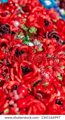 composition of small Handmade flowers, red and Burgundy roses, pearls, green leaves close up