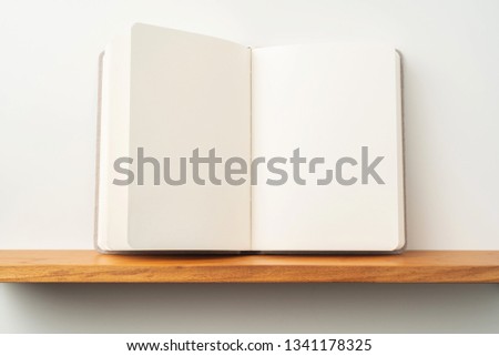 Design concept - front view of opened light red fabric notebook stand on bookshelf and grey wall for mockup, not 3D render