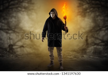 Man with burning flambeau coming from thicket and looking something