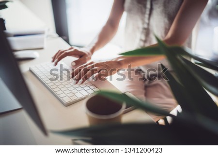 Confident young business woman using desktop computer in modern working place at coworking office.Blurred background