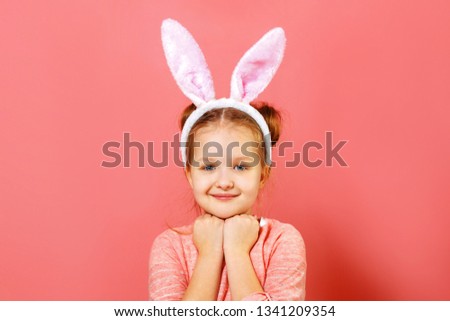 Portrait of a cute little child girl with bunny ears on a colar pink background. Easter concept. Close-up