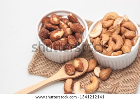 Almonds and cashew nut on the sackcloth and wood spoon on the white background, snack salted food