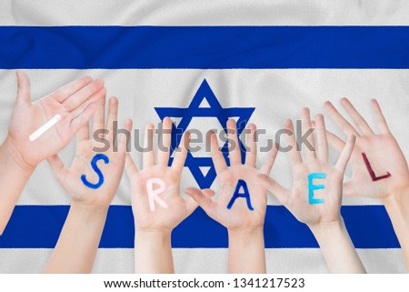 Israel inscription on the children's hands against the background of a waving flag of the Israel.
