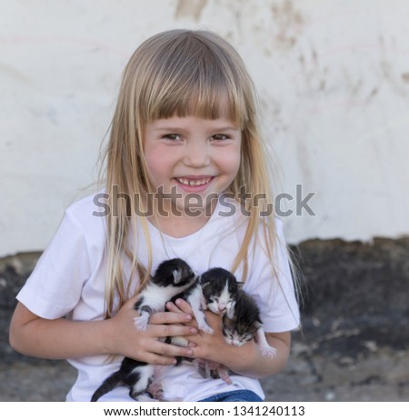Beautiful little blonde hair girl, has fun smile face, embraces and plays with kittens. Child and animals portrait. Happy amazing kids. Close up. 