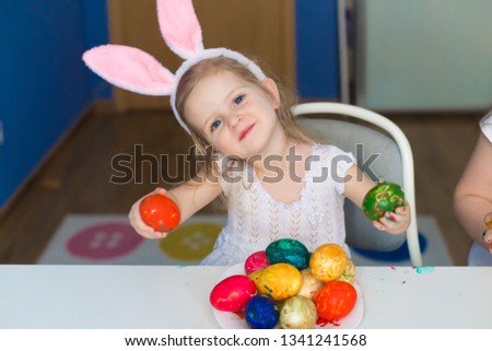 Beautiful little blonde girl, has happy face, pretty big blue eyes, white t-shirt, hare ears, paint brush. Child portrait and kids hobby concept. Amazing people. 