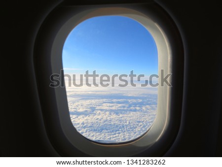 Airplane window with sky background. View from the airplane porthole. Window View From Passenger Seat. White clouds and blue sky.
