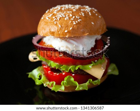 juicy burger with beef patty and fresh vegetables; consists of: buns, sweet sauce, onion rings, sweet pepper, lettuce, cheese, eggs
