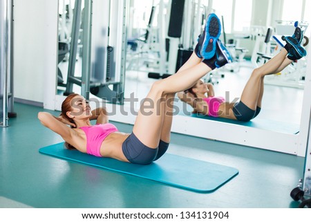 Gym fitness woman working out doing press fitness exercise smiling happy during workout. Young fitness model training in fitness center.