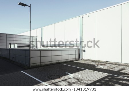 This architecture image is minimalist and has easy geometrical lines for the eye to follow.  As we can see due to the signs, it is a partking lot for handicapped.