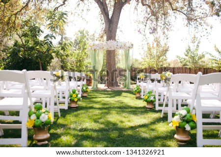 Beautifully decorated wedding ceremony location under a large oak tree, wide view.  Royalty-Free Stock Photo #1341326921